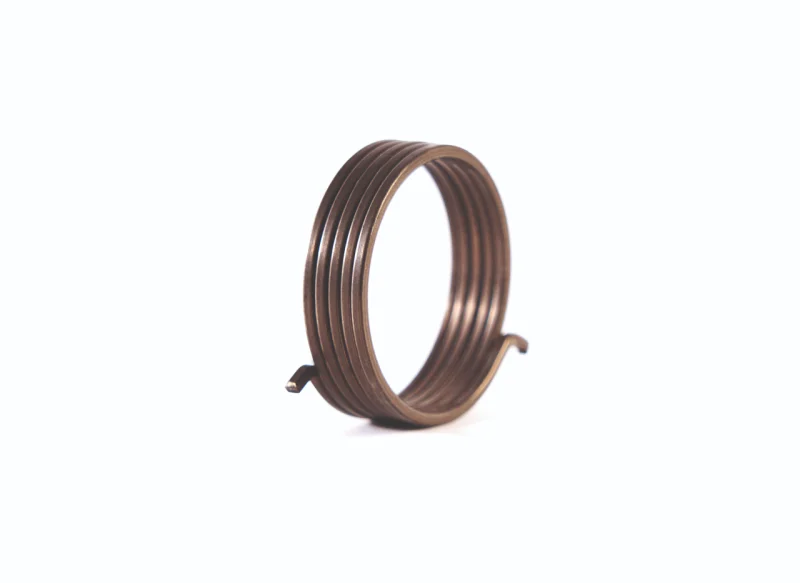 Composición de diversos muelles de torsión sobre fondo blanco, incluyendo un muelle de torsión doble en primer plano, modelos pavonados en negro, piezas de acero inoxidable y pequeños muelles de precisión con diferentes ángulos de patas.